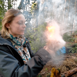 a participant blowing a piece of wheat to start a fire